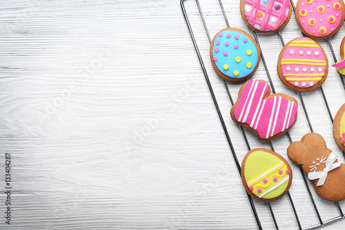 Decorative gingerbread Easter cookies on baking wire rack and white wooden background