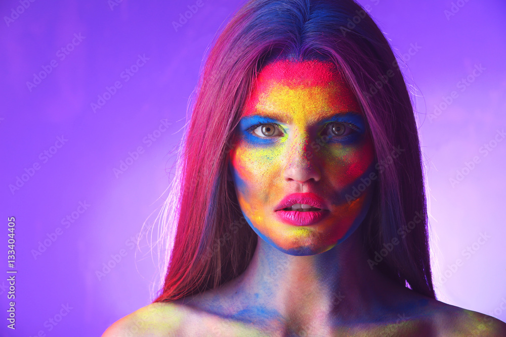 Obraz premium Portrait of attractive young woman with bright facial body-art on purple background