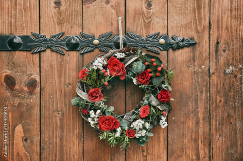 Floral wreath with beautiful flowers hanging on wooden background
