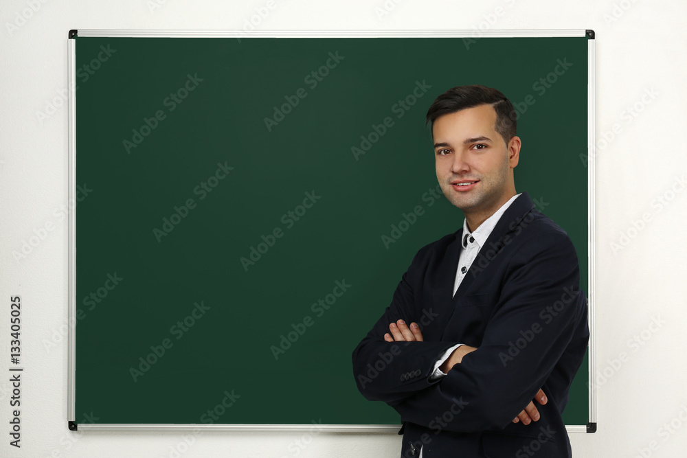 Handsome young teacher near blackboard in classroom Handsome young teacher near blackboard in classroom