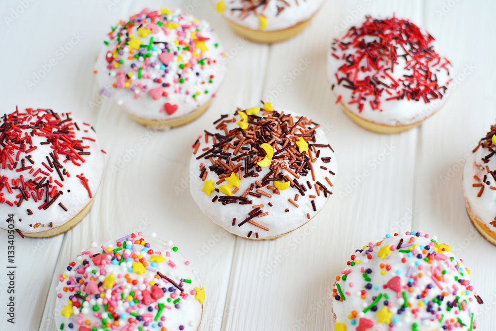 Cupcakes with white cream and sprinkles on white background Cupcakes with white cream and sprinkles on white background