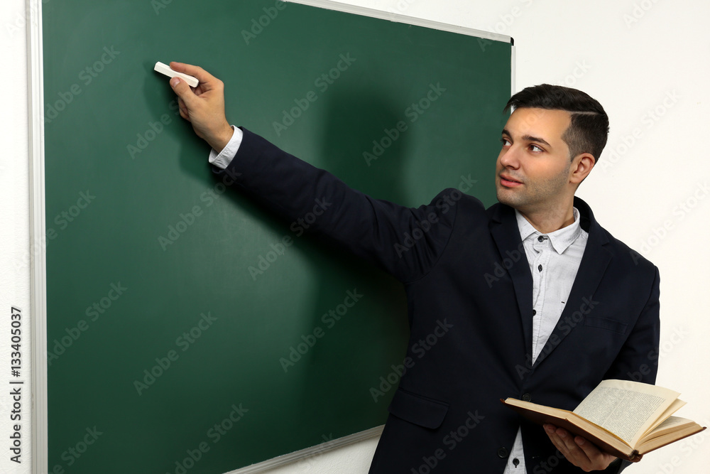 Handsome young teacher near blackboard in classroom Handsome young teacher near blackboard in classroom