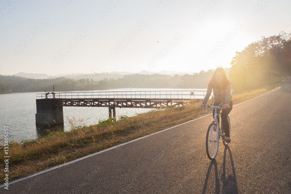 young woman ride bicycle on load  in morning, concept of Asian lifestyle.