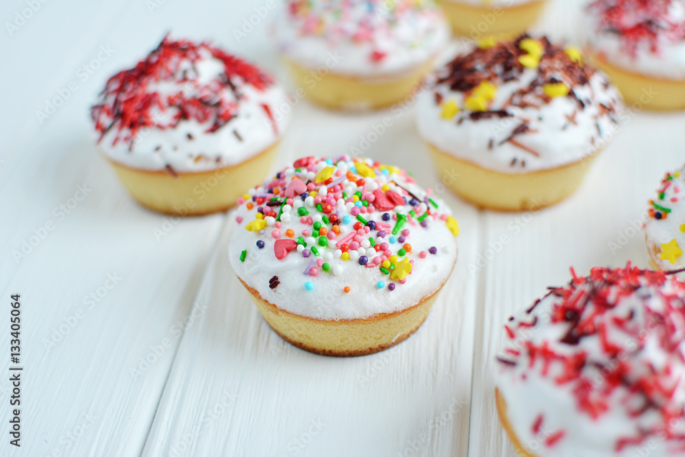 Cupcakes with white cream  and sprinkles on white background