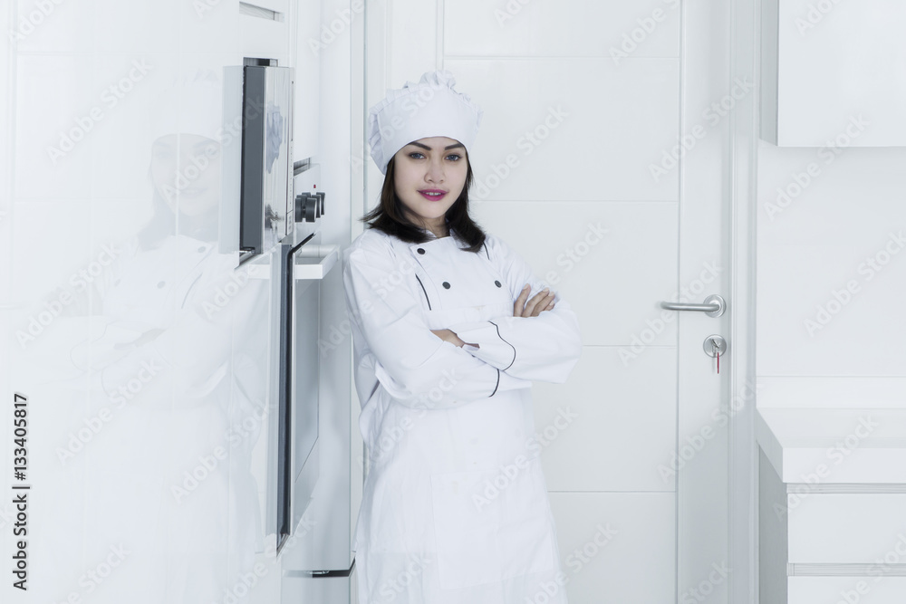 Beautiful female baker standing in kitchen Beautiful female baker standing in kitchen