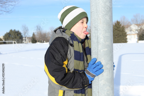 Boy sticking his tongue on a metal pole