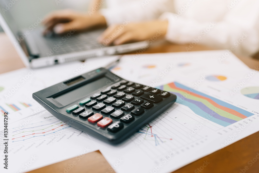 Close up shot of calculator with businesswoman working in background Close up shot of calculator with businesswoman working in background
