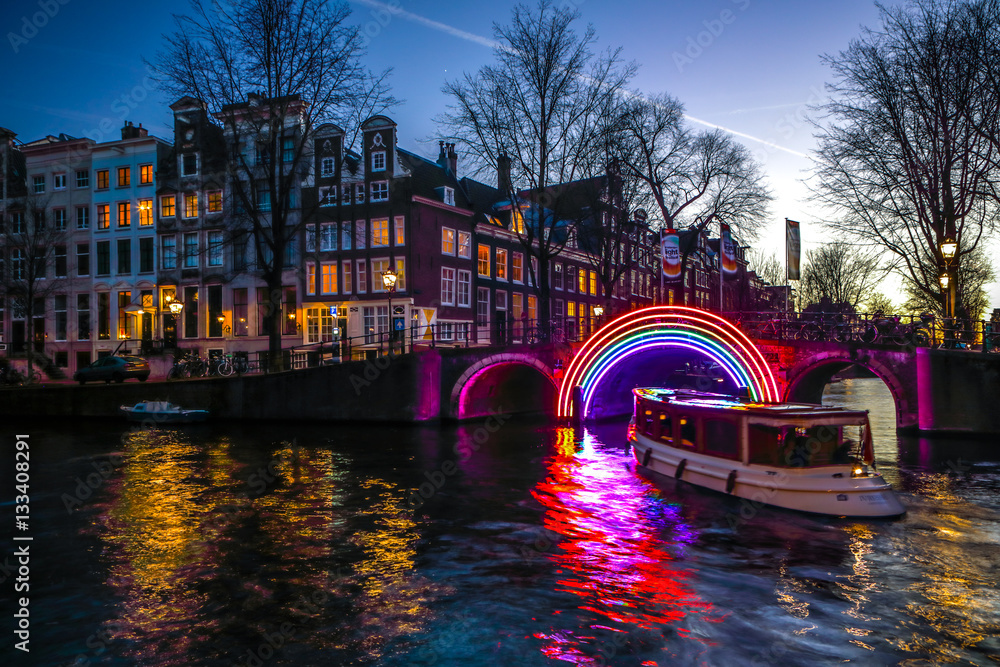 Fototapeta premium AMSTERDAM, NETHERLANDS - JANUARY 10, 2017: Cruise boats rush in night canals. Light installations on night canals of Amsterdam within Light Festival. January 10, 2017 in Amsterdam - Netherland.
