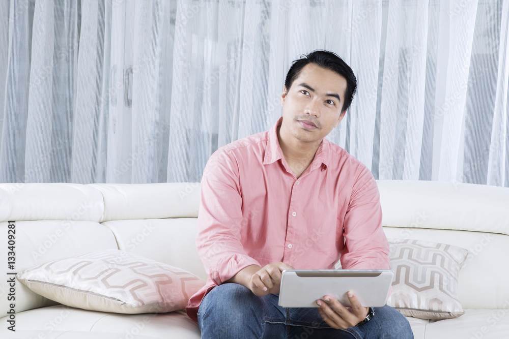 Obraz premium Handsome man using tablet on couch