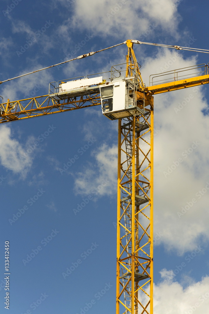 Yellow crane on construction site with blue sky background