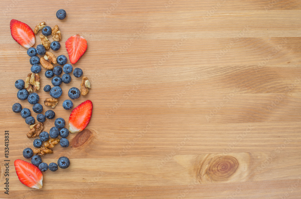 Fototapeta premium Strawberries, blueberries and nuts on wooden background.