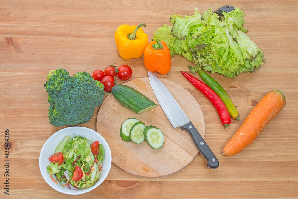 © naataali - Chopped salad and whole fresh vegetables on wooden table. Top view.