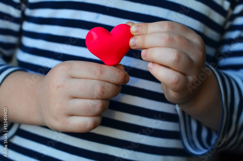 child holding a small pink heart. symbol of love  family  hope. Backgrounds for cards on Valentine s Day. Backgrounds for social posters about the preservation of the family and children.