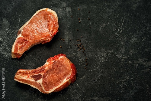 Two raw pork steak on a dark black background with free space for your inscription