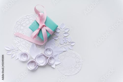 a gift on a white napkin and white paper flowers