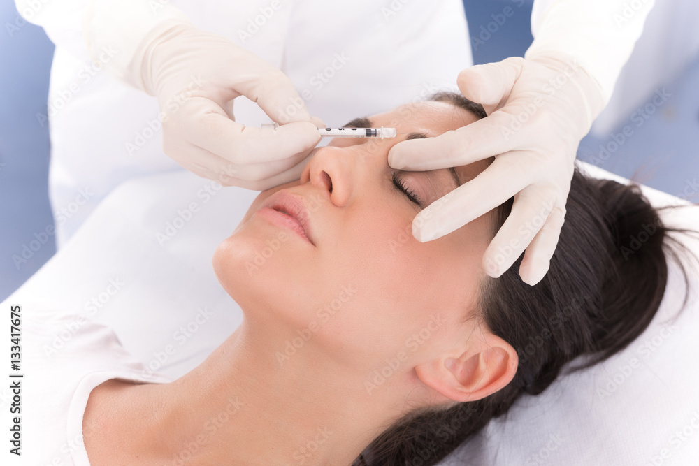 Cosmetologist injecting cosmetic treatment in female face