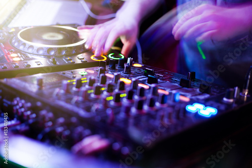 DJ playing music at mixer closeup and mixes the track in the nightclub at party
