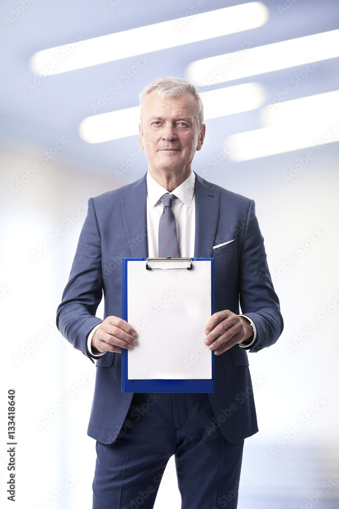 Man with clipboard. Shot of a senior sales man in his hand a clipboard with a blank paper while standing at office. Man with clipboard. Shot of a senior sales man in his hand a clipboard with a blank paper while standing at office.