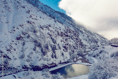 Little pictersque lake in snowy mountains photo