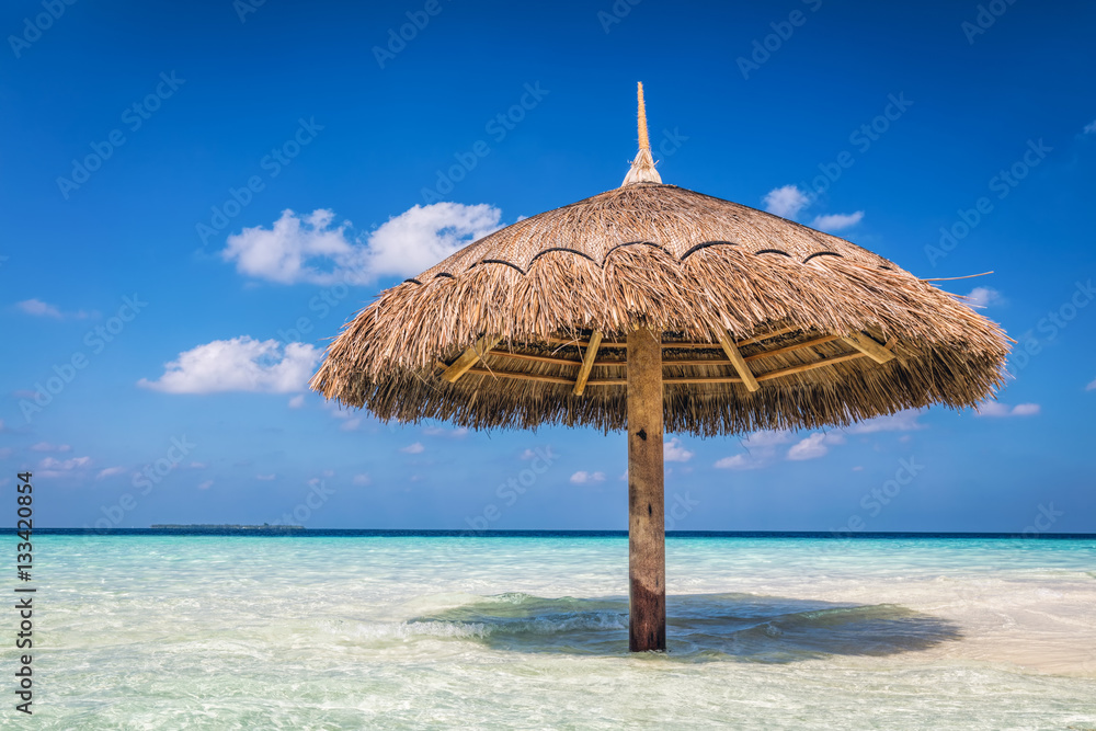 Tropical sandbank island with sunshade umbrella. Indian Ocean, Maldives.