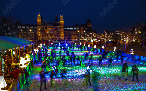 AMSTERDAM, THE NETHERLANDS - JANUARY 12, 2017: Many people skate on winter ice skating rink at night in front of the Rijksmuseum, a popular touristic destination in Amsterdam, The Netherlands. photo