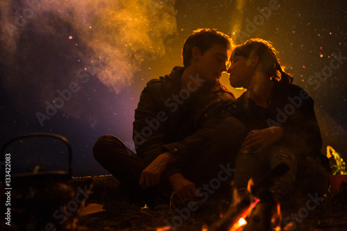 man and woman kiss near the fire on a background of the sky