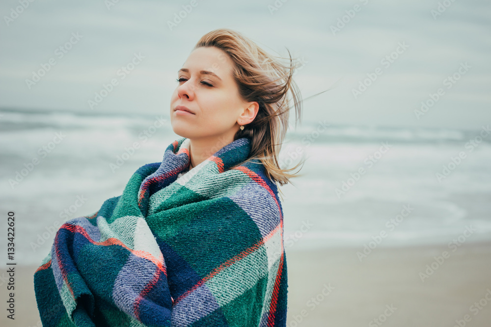 A girl wrapped in a blanket on the background of the sea
