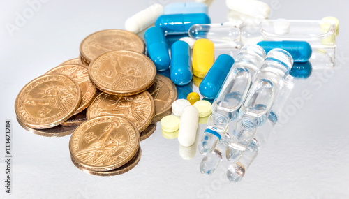 Pills, capsules, ampoules and coins on reflective background. Me