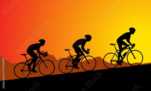 Bike racers climbing to the top, at sunset