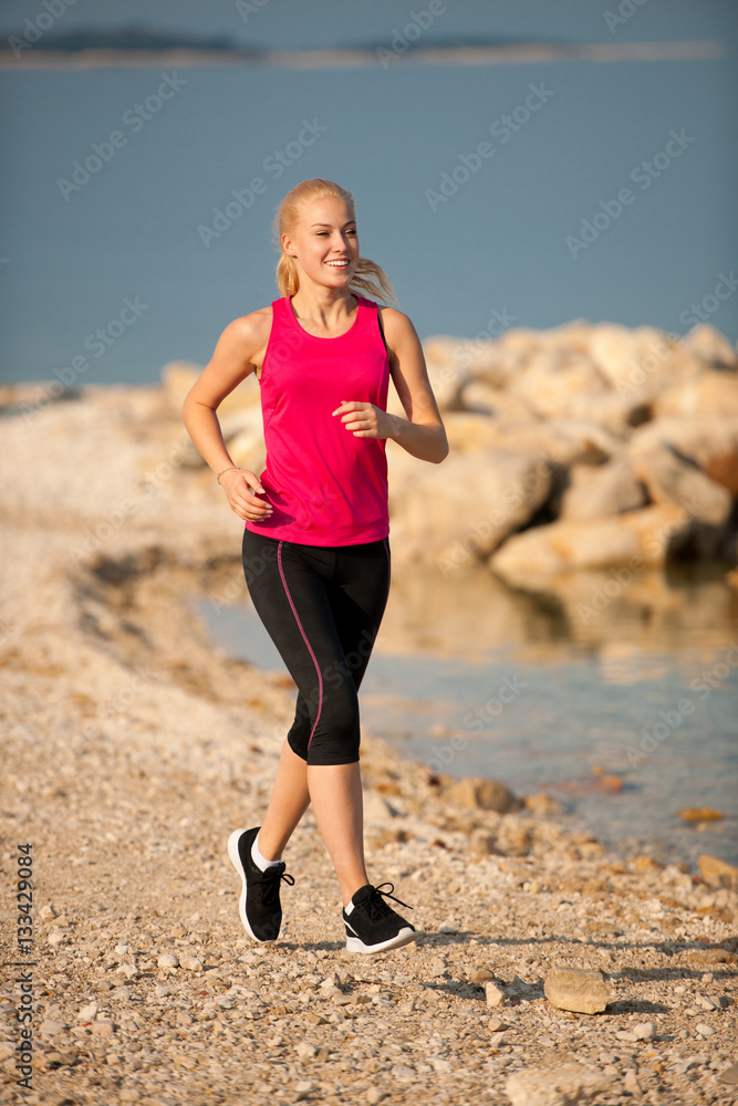 jogging in th beach - woman runns near sea on early summer morni