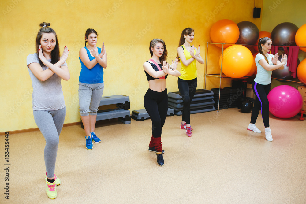 Fototapeta premium smiling people with coach dancing zumba in gym or studio