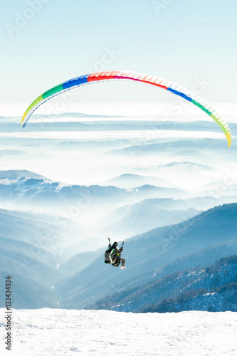Paragliders launched into air from snowy slope of a mountain
