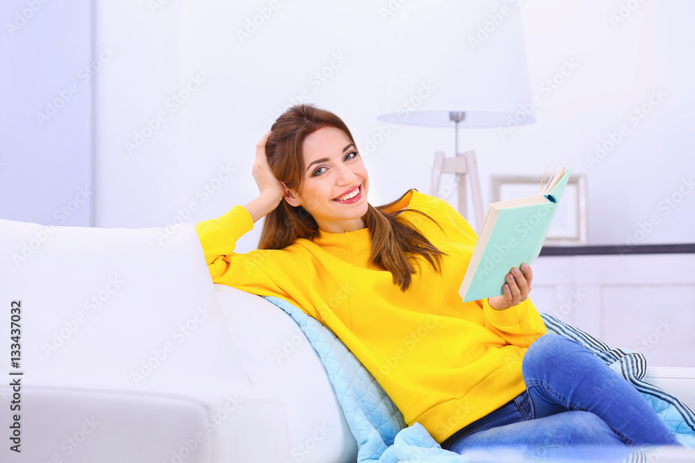 Young woman reading interesting book on sofa at home Young woman reading interesting book on sofa at home