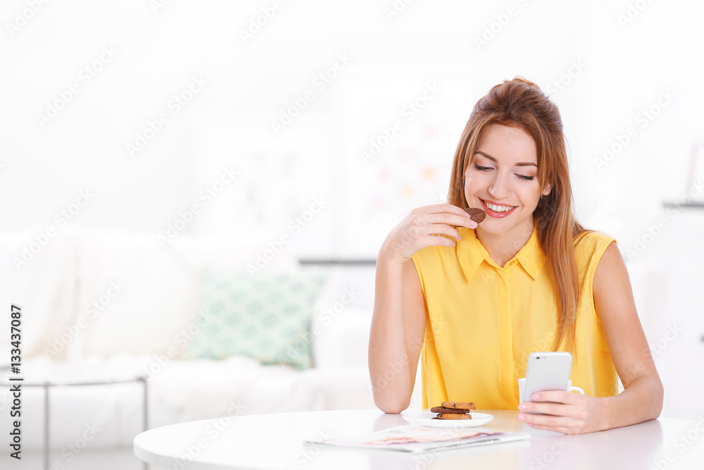 Young beautiful woman with cup of coffee using smart phone and sitting at table Young beautiful woman with cup of coffee using smart phone and sitting at table