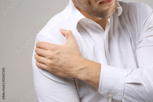 Young man suffering from pain in shoulder, closeup © Africa Studio