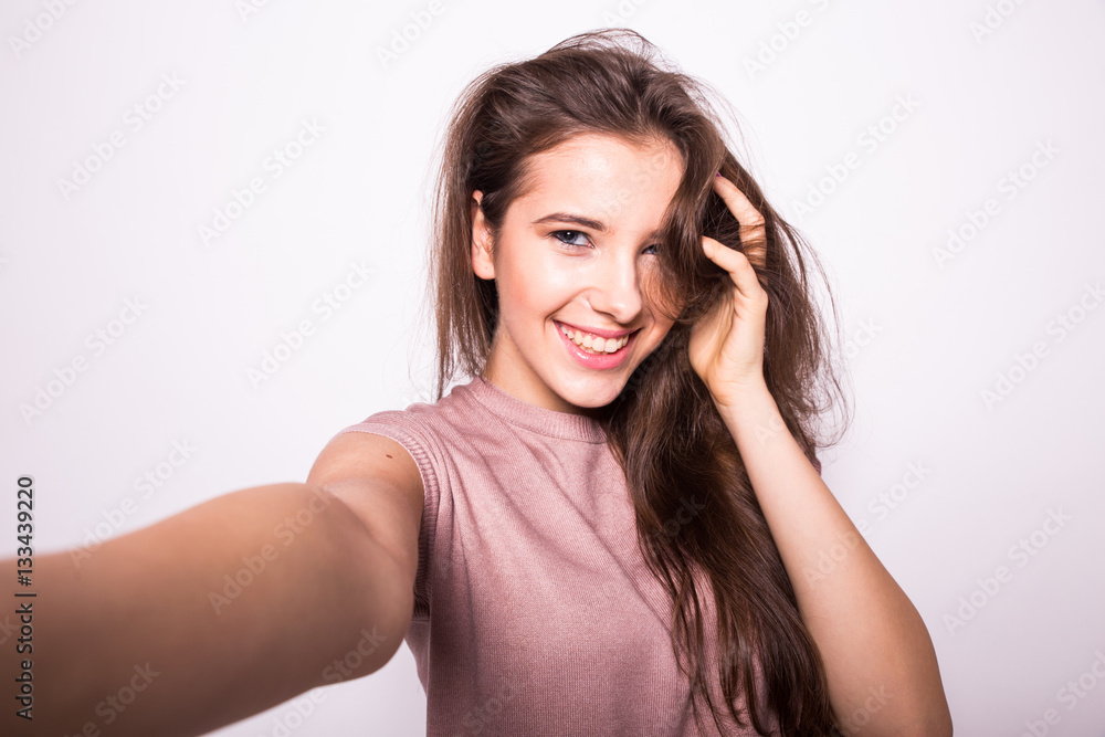 Young happy smile girl take selfie on white background Young happy smile girl take selfie on white background