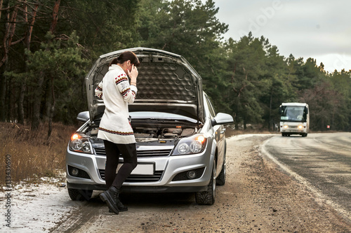 young woman standing near the broken car. The girl opened the hood and look at the engine. Refit woman car
