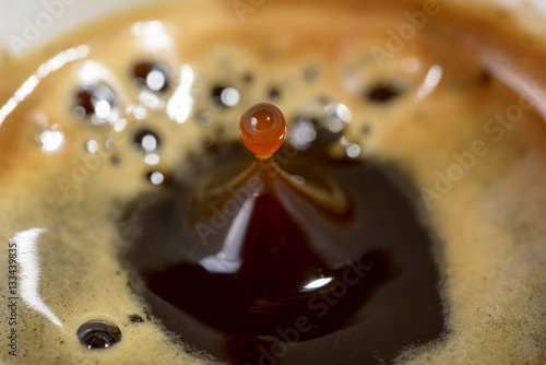 macro drop of coffee in fall toward the cup of coffee