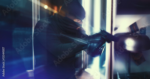Einbrecher mit Pistole und Taschenlampe