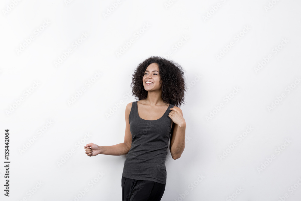 Smiling woman looking away while standing at white wall Smiling woman looking away while standing at white wall