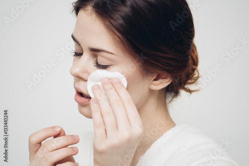 women wipe face with a cotton disc, make-up removal