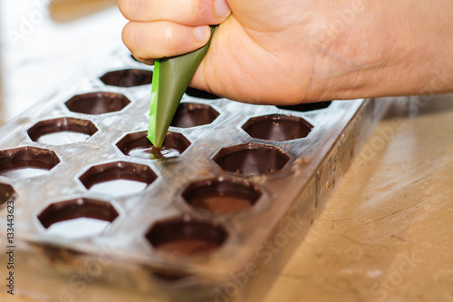 Slika na platnu Filling out candy mold form with the chocolate