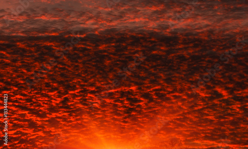 Fiery orange sunset colorful and speckled clouds. Beautiful sk