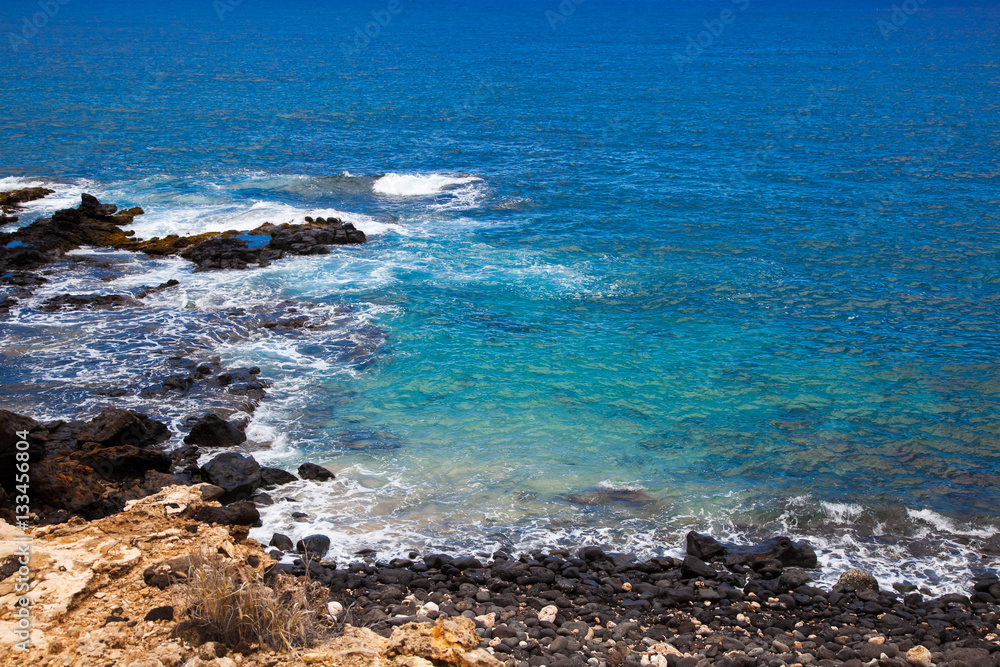 Lanai Hawaii.  A rock beach.  Shipwreck beach.  Blue water.  Black rocks.