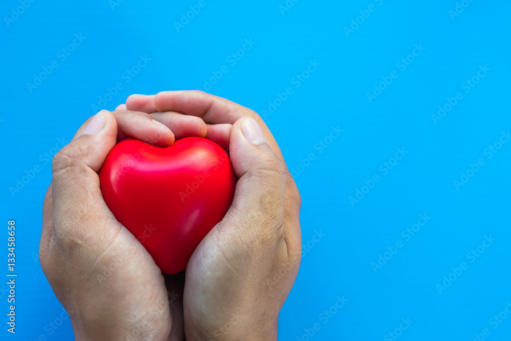 Obraz premium man hands giving red heart on coloured background