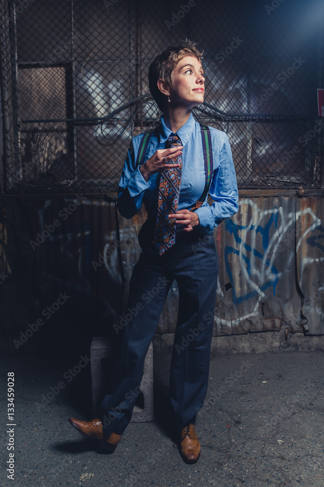 Young androgynous woman dressed in mens clothing in a grungy, urban outdoor location Young androgynous woman dressed in mens clothing in a grungy, urban outdoor location
