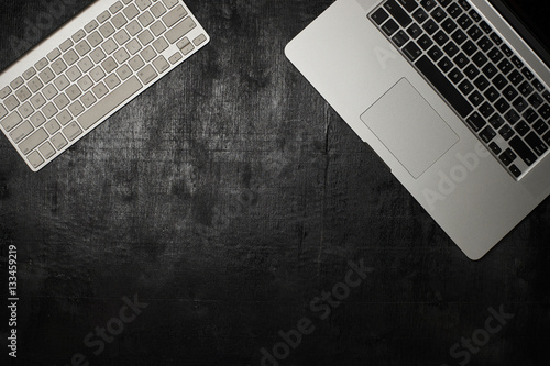 Wooden black office desk table with laptop and keyboard. Top view photo