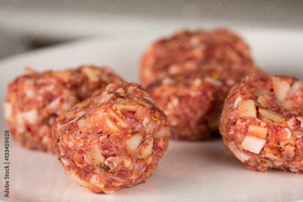 Minced meatballs on a plain white plate, tasty seasoned raw meat special Minced meatballs on a plain white plate, tasty seasoned raw meat special