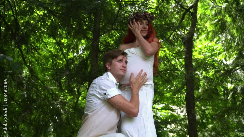 Pregnant couple in green forest at summer. Closeup of man hearing pregnant belly. Husband holding pregnant woman belly outdoor. Pregnancy concept. Love couple at park Pregnant couple in green forest at summer. Closeup of man hearing pregnant belly. Husband holding pregnant woman belly outdoor. Pregnancy concept. Love couple at park