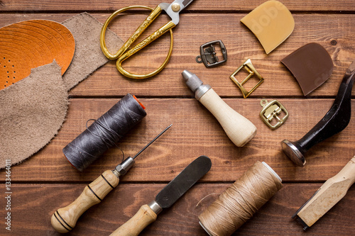 leather craft instruments on wooden background top view